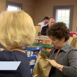 Volunteers pack brown bags with food for veterans